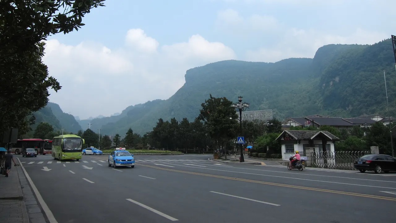 Taxi e autobus su una strada di Wulingyuan sotto le creste montuose boscose