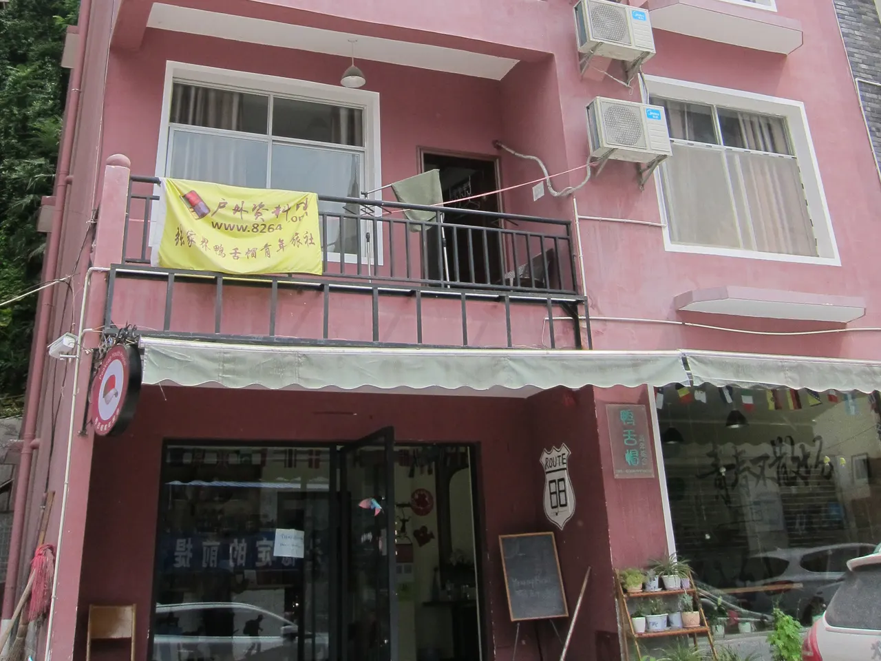 Fachada rosa de un hostal en Wulingyuan con balcones, ropa tendida y aparatos de aire acondicionado, fotografiada en 2016