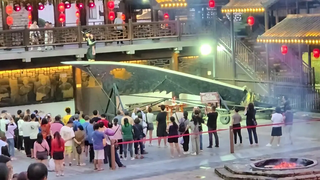 Público junto a una plataforma curva al aire libre y un brasero encendido en Charming Xiangxi