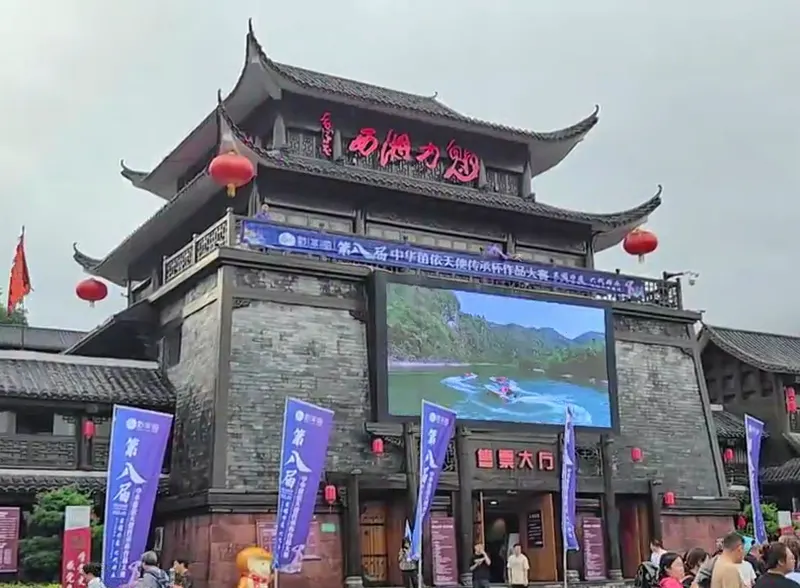 Fachada del teatro Charming Xiangxi con el letrero del tejado y la entrada a las taquillas