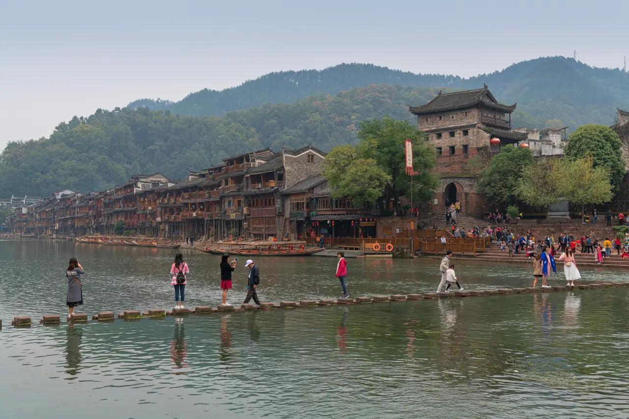 Paso de piedras sobre el río Tuojiang, casas sobre pilares y torre de una puerta en Fenghuang