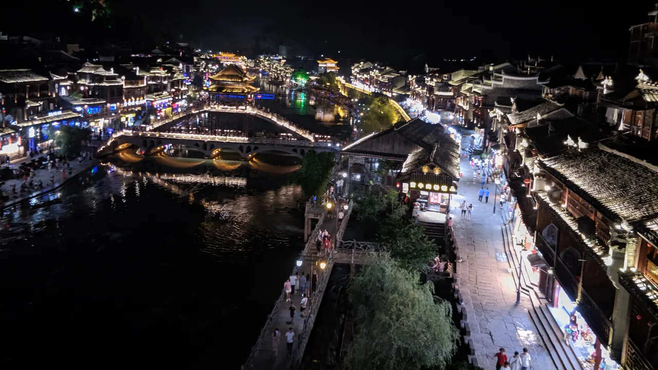 El Tuojiang de noche con un puente y tejados iluminados junto al río