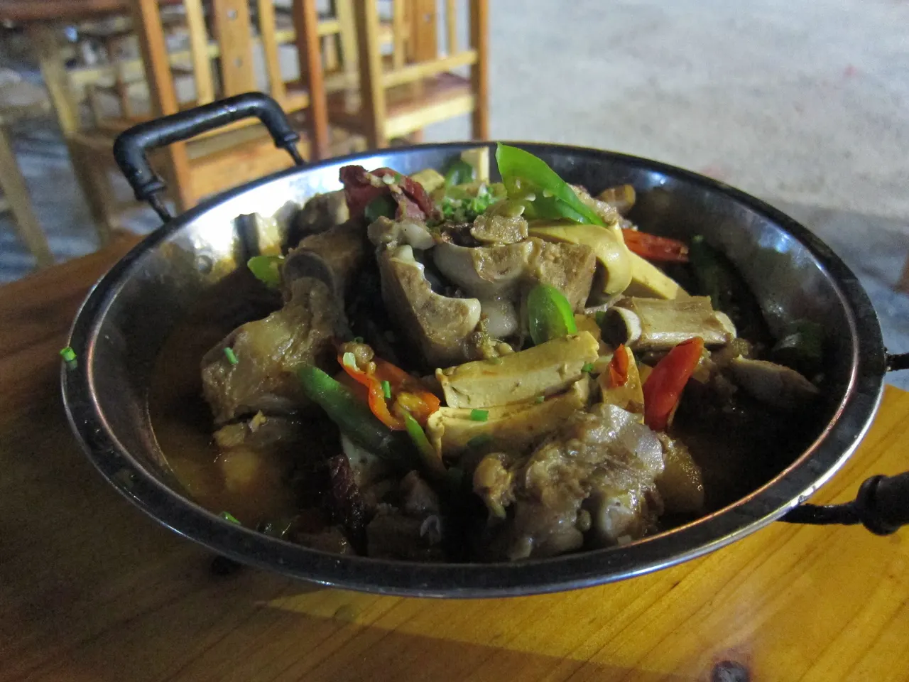 Sanxiaguo con carne e peperoni rossi e verdi in una padella di metallo a Wulingyuan