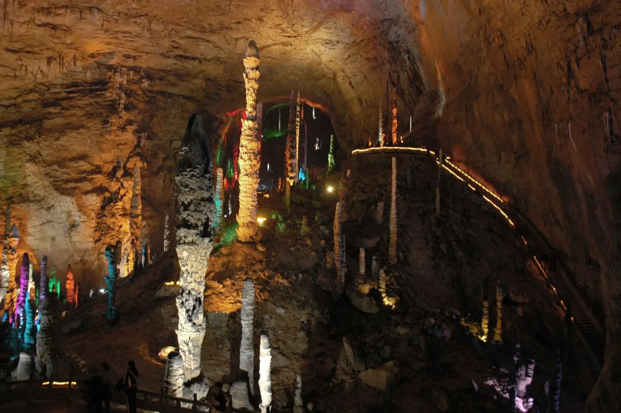 Estalagmitas iluminadas y una pasarela elevada en la cueva Huanglong