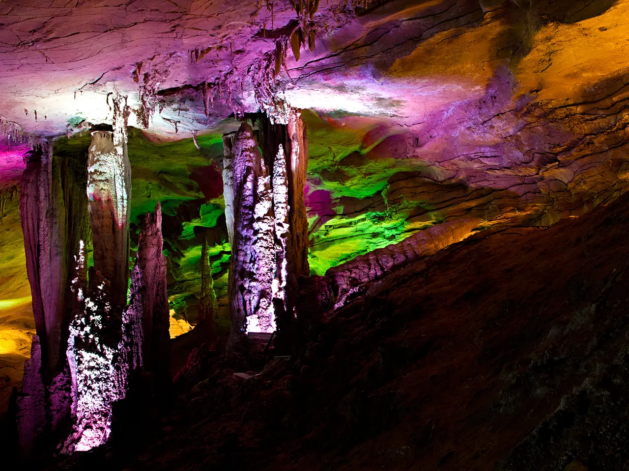 Stalagmiti e pareti illuminate da luci colorate nella grotta Huanglong