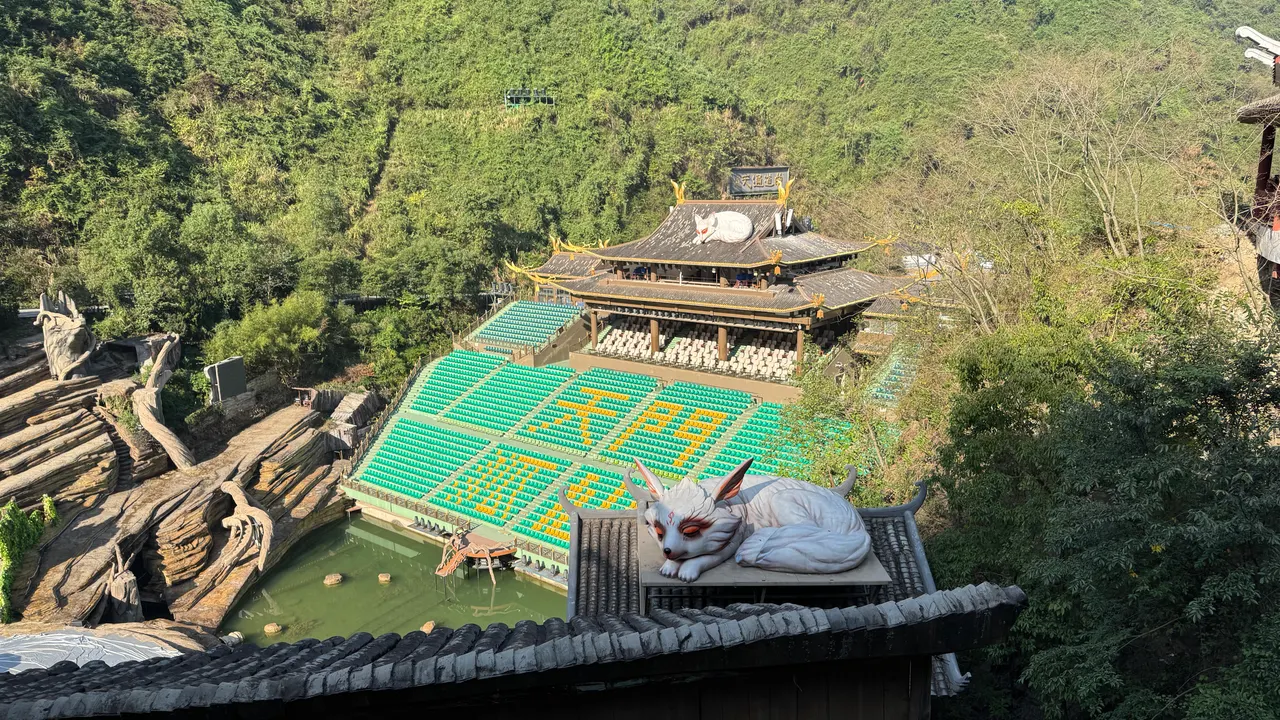 Asientos vacíos al aire libre, escenario de roca y zorro blanco en el tejado del teatro Hada Zorro de Tianmen durante el día