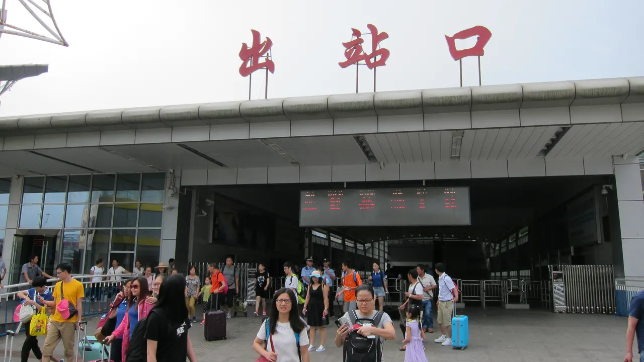 Viaggiatori con bagagli davanti all’uscita della stazione di Zhangjiajie, indicata da 出站口, nel 2016