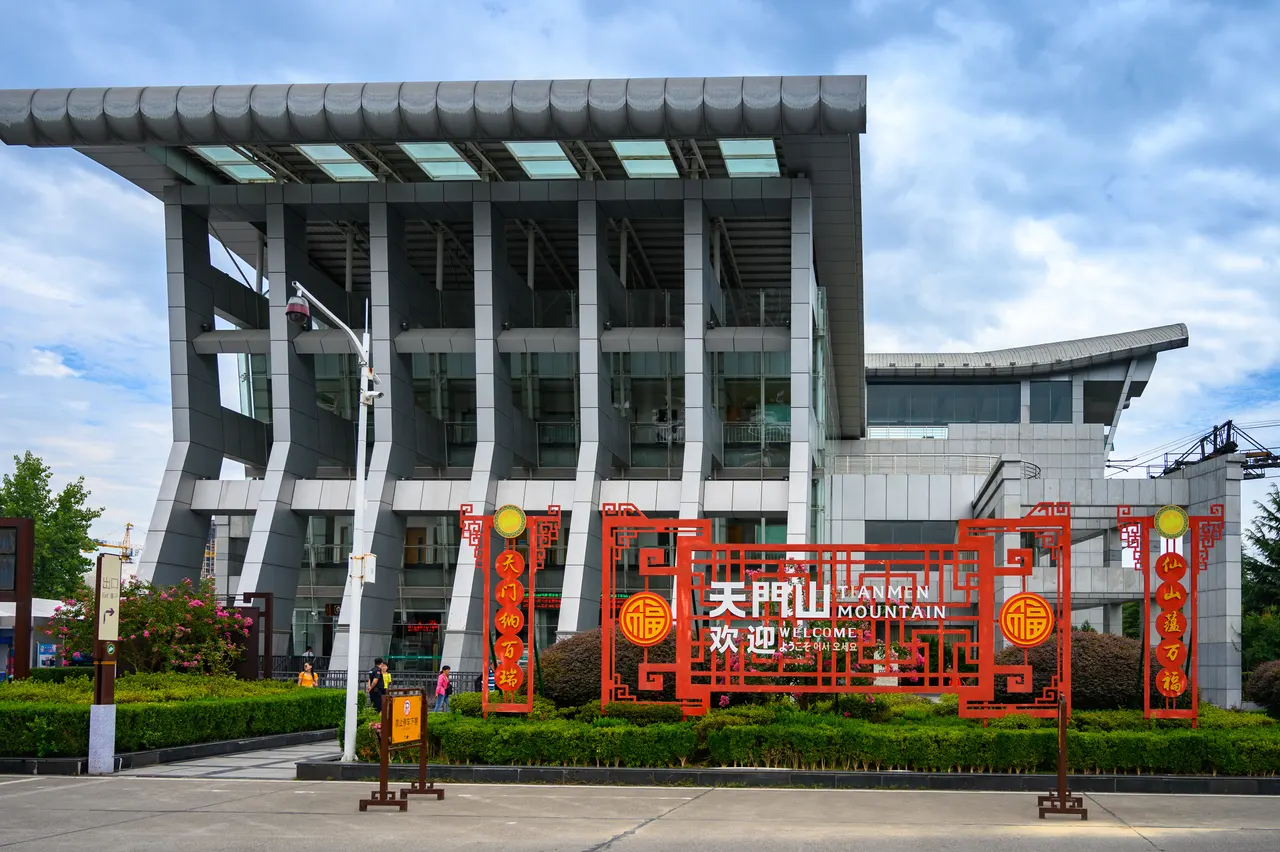 Stazione inferiore della funivia del Tianmen in città e insegna rossa di benvenuto, fotografate nel 2019
