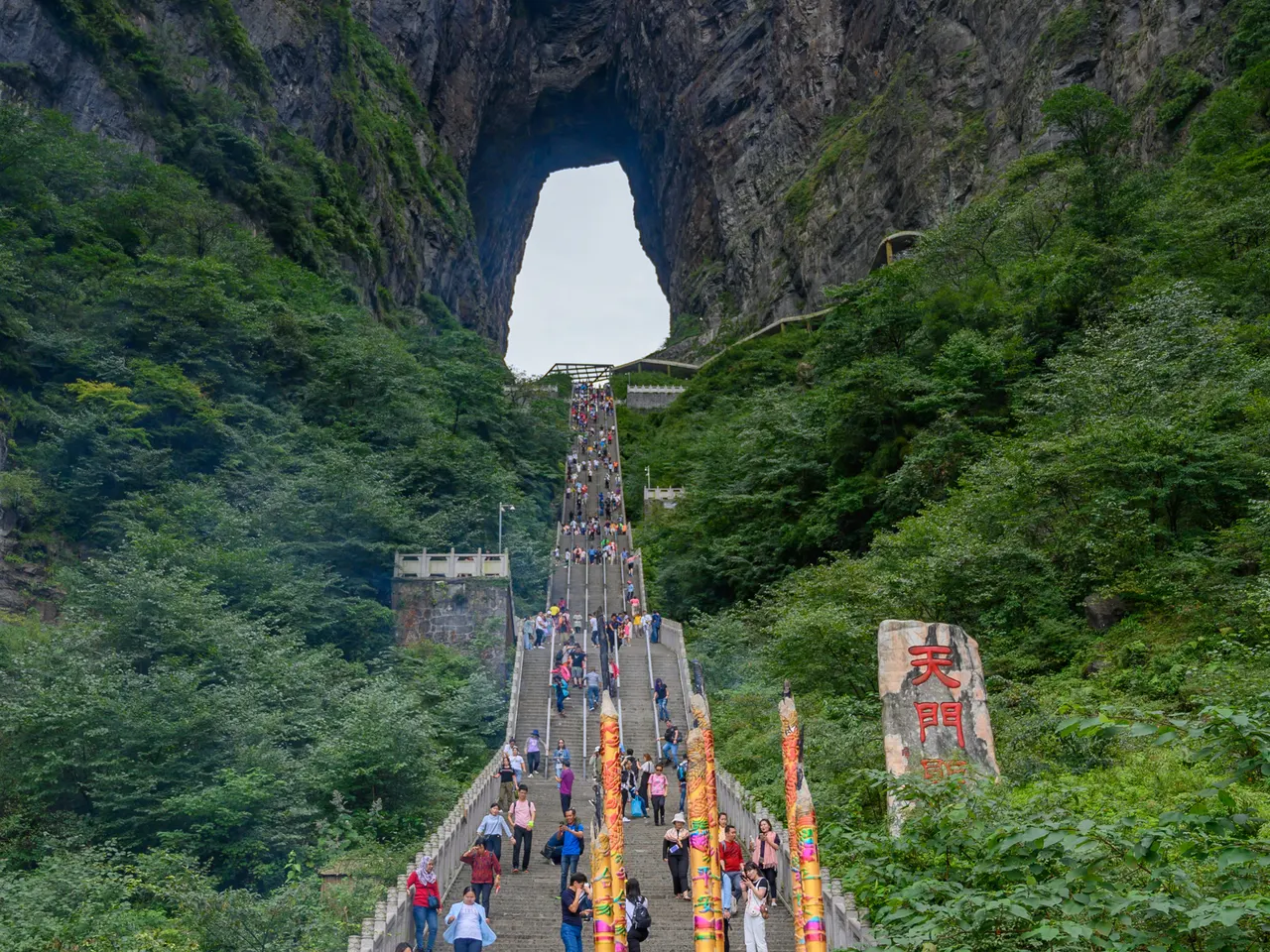 Visitatori sulla ripida scalinata di pietra sotto la grotta di Tianmen