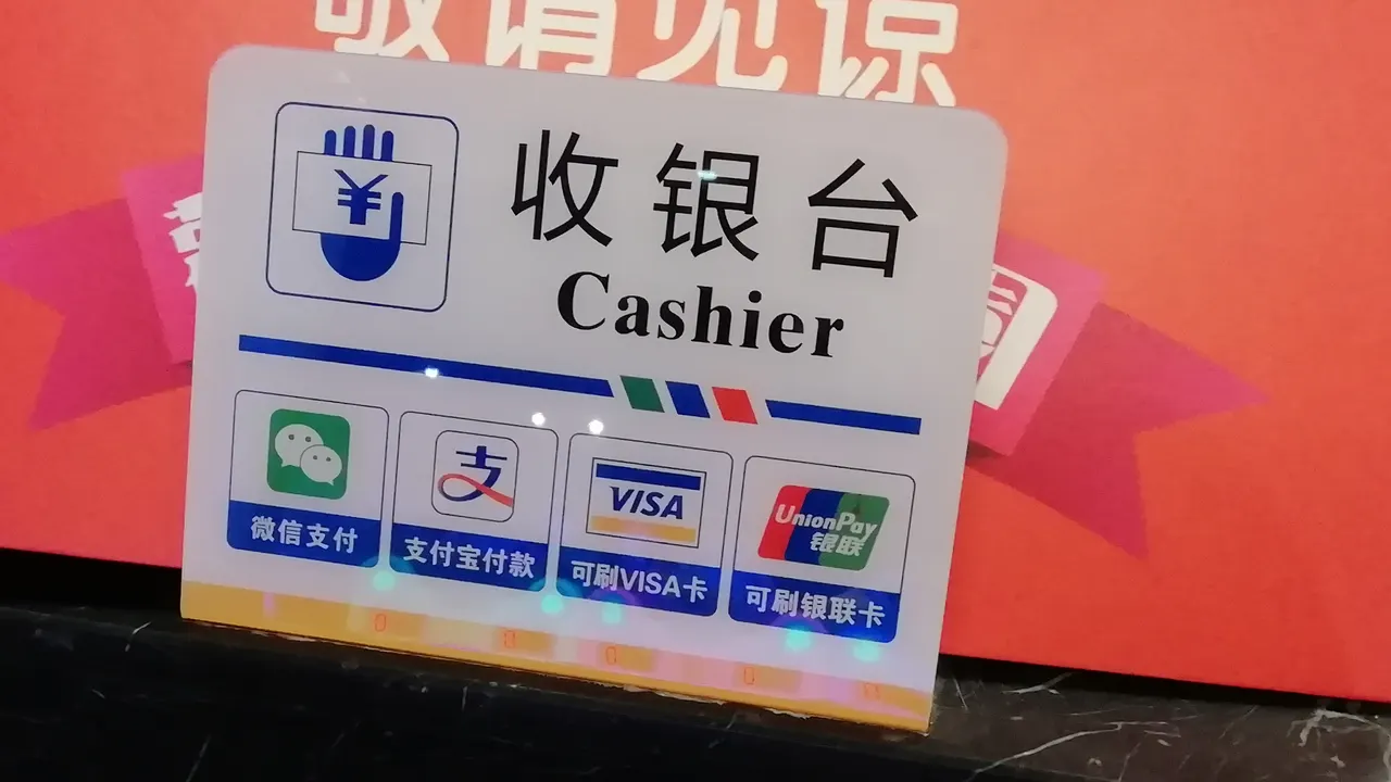 Cartello alla cassa con il logo verde di WeChat Pay e altri metodi di pagamento