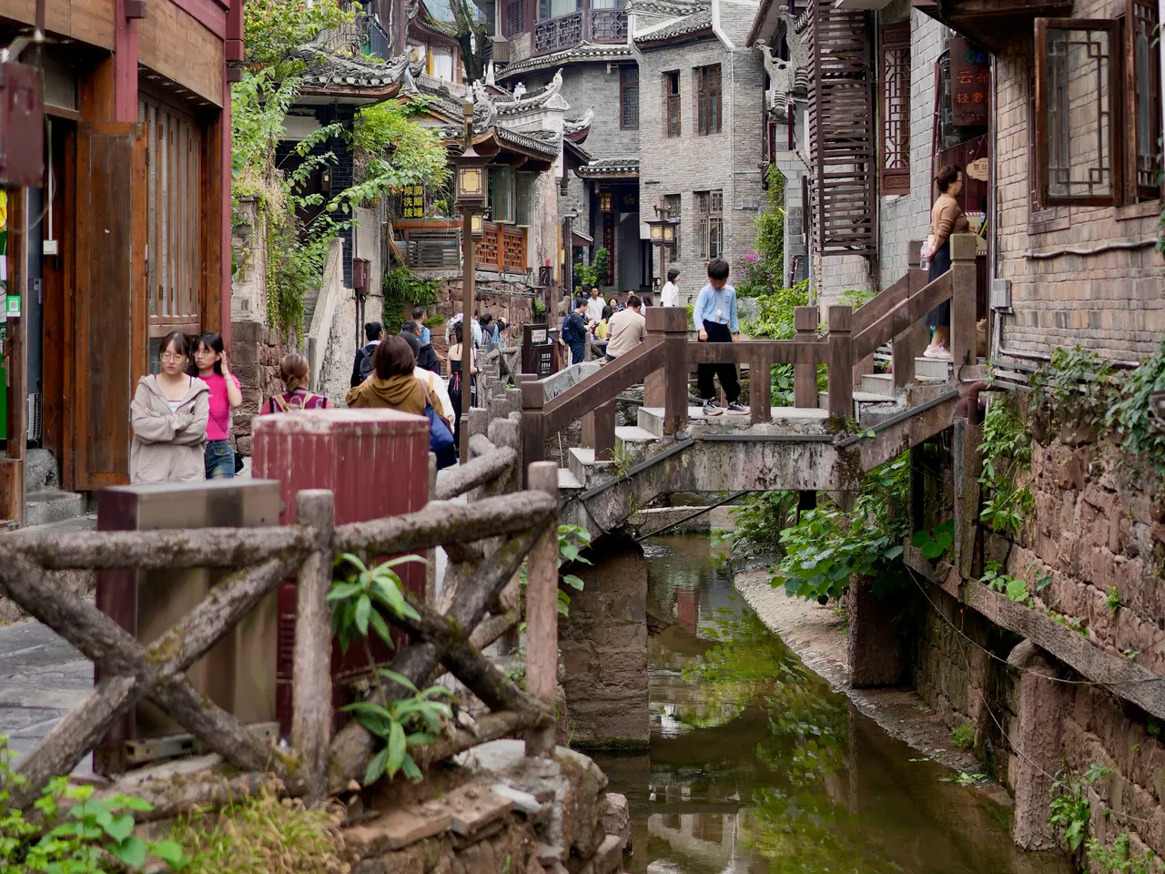 Camino de piedra y escalones de un puente junto a un canal del casco antiguo de Fenghuang